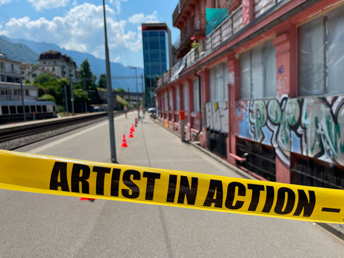 vibrant mural painting over a classified building to repress vandalism / artist at work